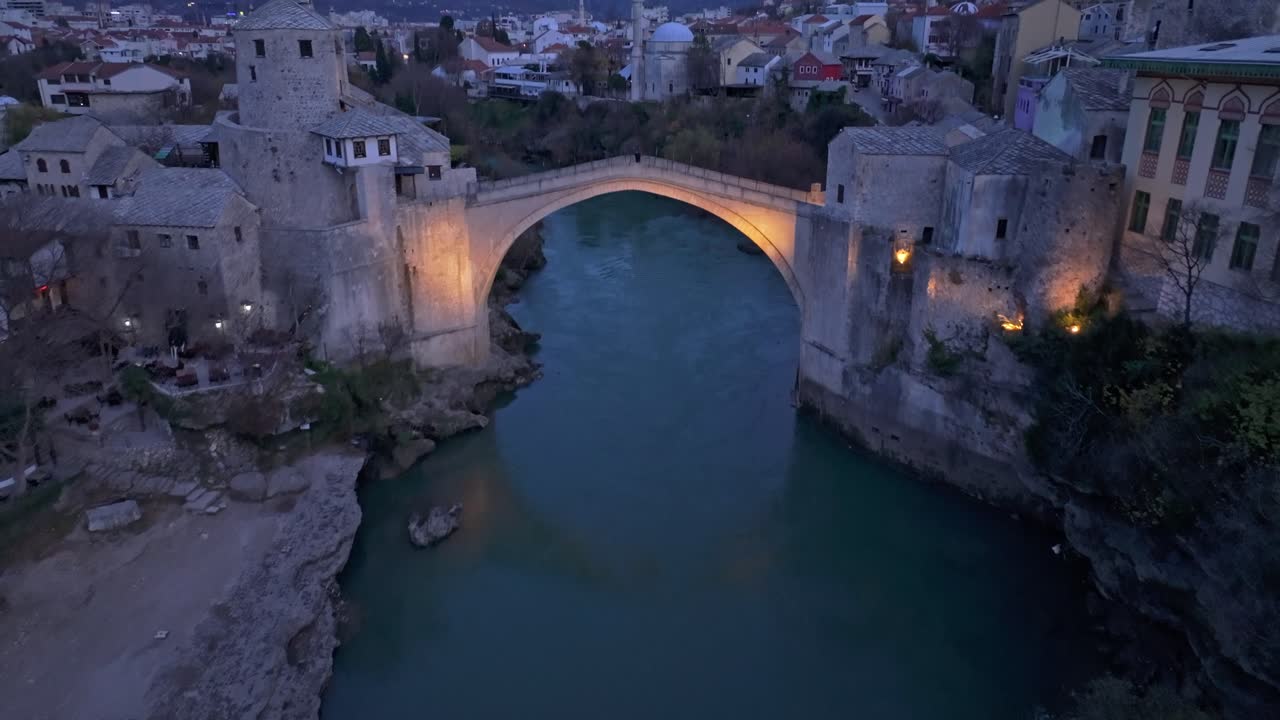 Ripresa drone del Ponte Stari Most che risplende al crepuscolo sul fiume Narenta.