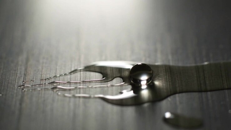 Flattening metallic droplet driven by capillary forces on brushed metal, forming filaments