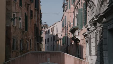 historic narrow street with weathered buildings and green shutters in venice, italy