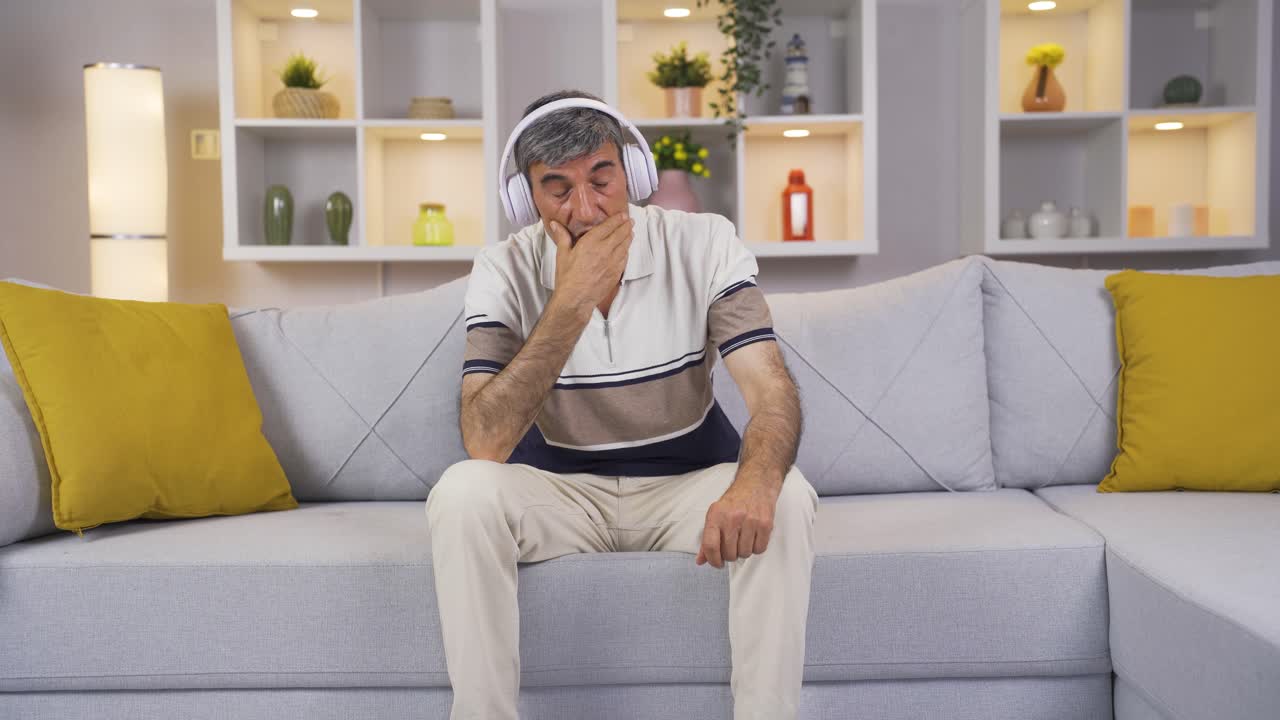 Anziano che ascolta musica con le cuffie è infelice e triste