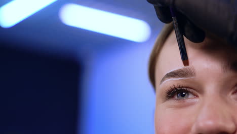 upper part of a female face with white lines around eyebrows. salon procedures for the eyebrows. close up.