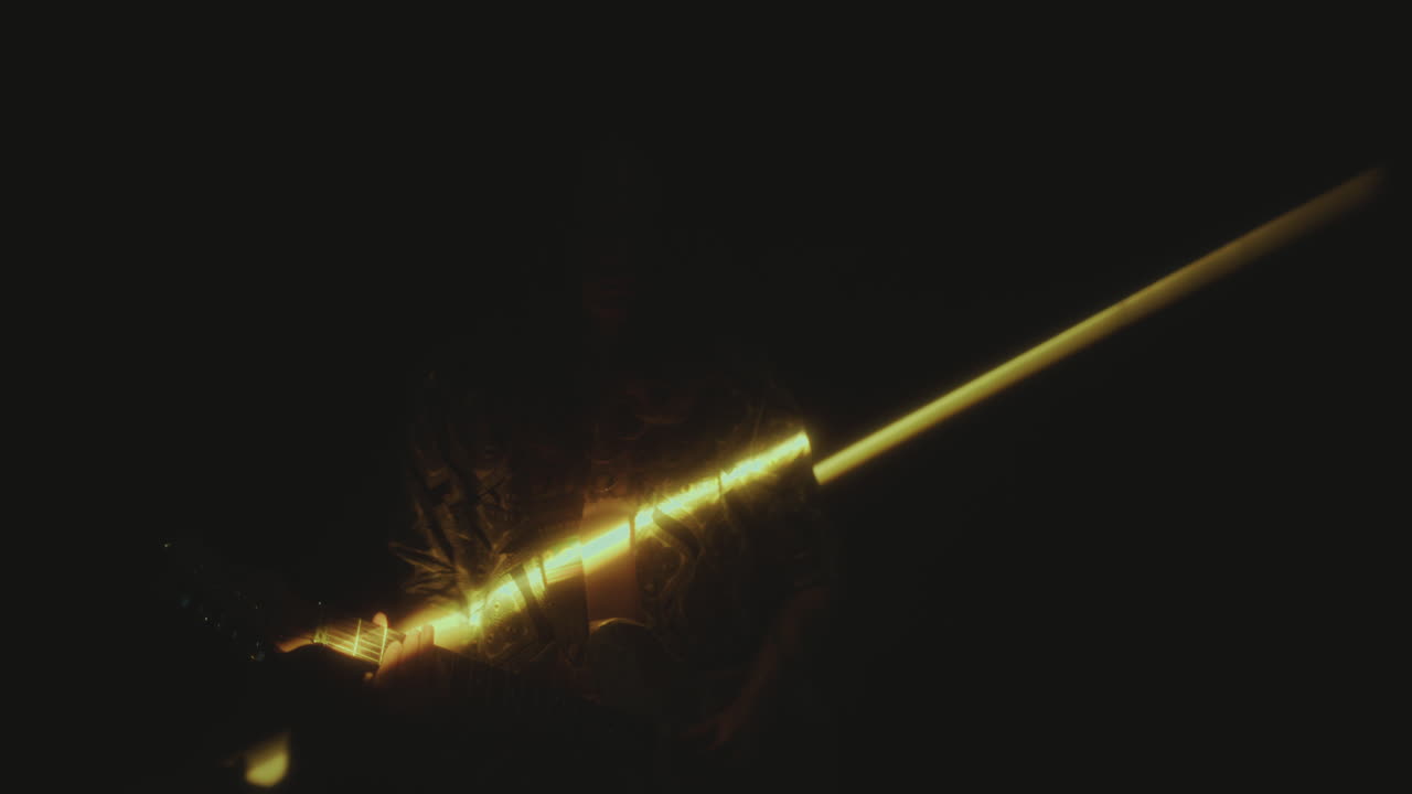 Rock Musician Playing Electric Guitar in Dark Room with Light Beam