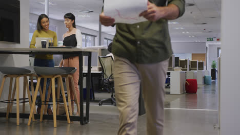 Diverse-male-and-female-business-colleagues-talking-and-walking-in-office