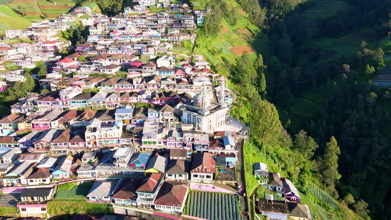toma de drones de casas coloridas ubicadas en campos de montaña, mezquita y plantación durante la puesta de sol - butuh, indonesia
