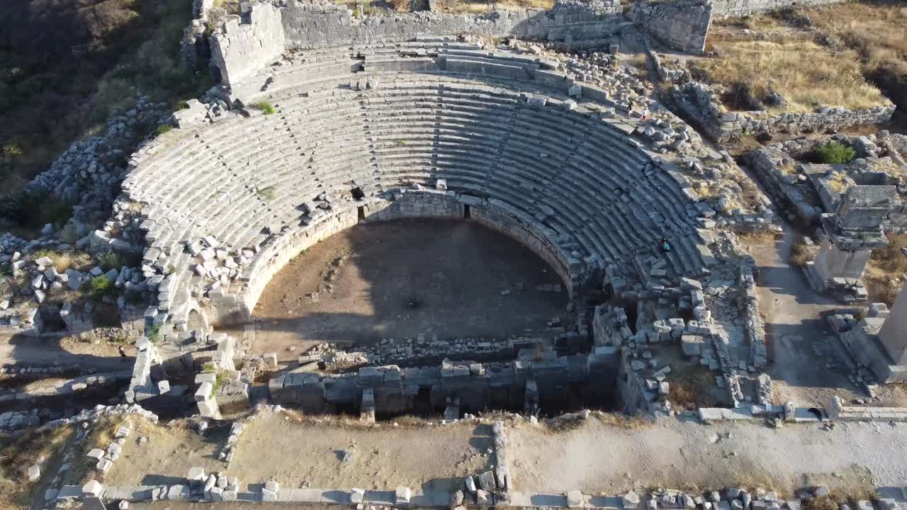 Aerial footage showcasing the ancient Roman amphitheater in Myra, Turkey. Stunning stone seating, ruins, and vegetation captured in a dynamic drone video highlighting historic grandeur