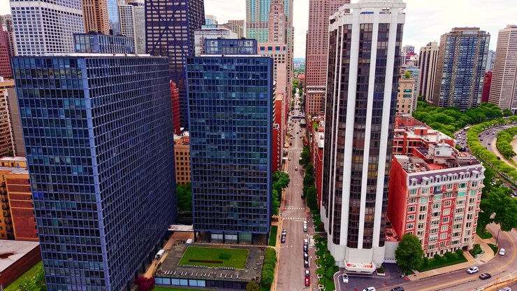 Torres de apartamentos de alto padrão ao longo da rua da cidade, Chicago. Edifícios residenciais de vidro, estrada com veículos, árvores verdes e parque