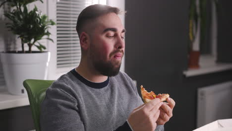 homem faminto descansando e comendo pizza saborosa no escritório 3