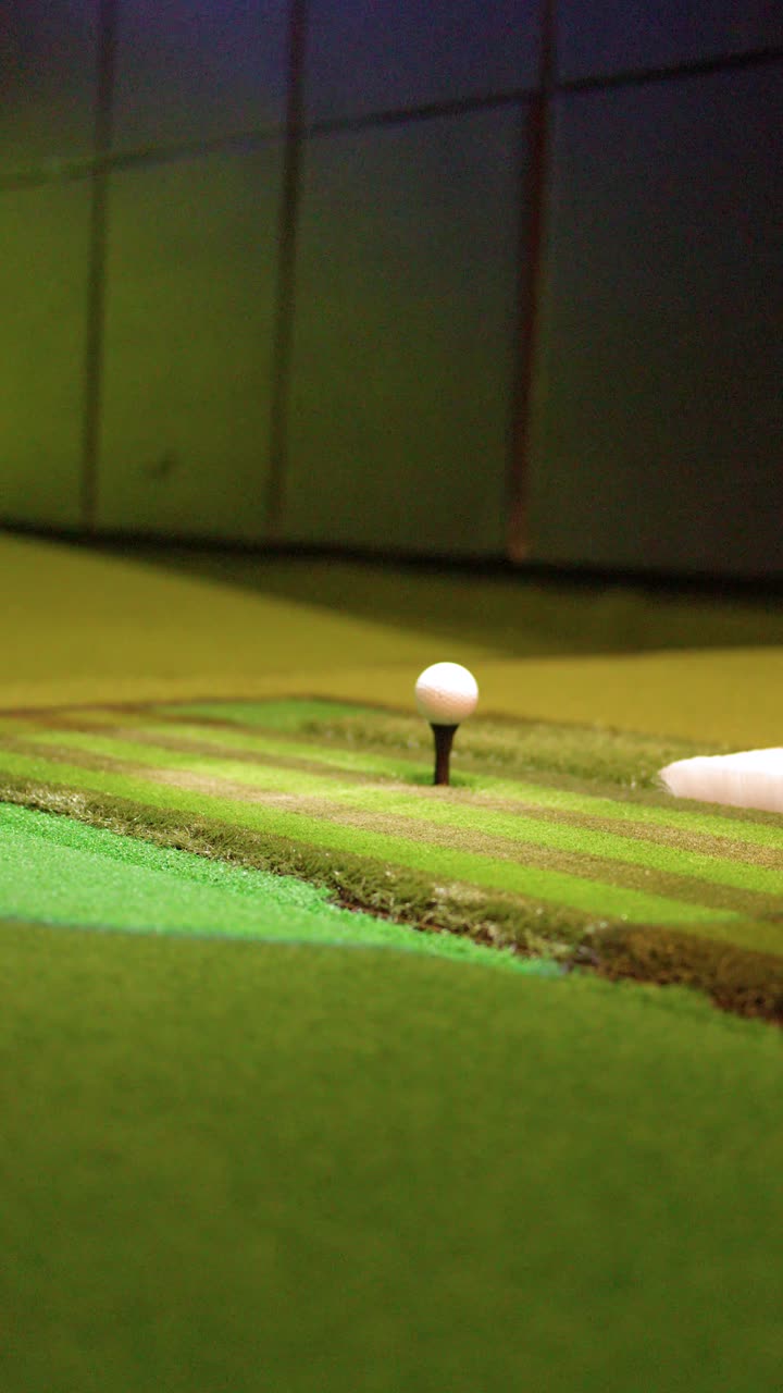 En golfball stiger automatisk opp på en peg inne i en moderne innendørs virtuell golfsimulator