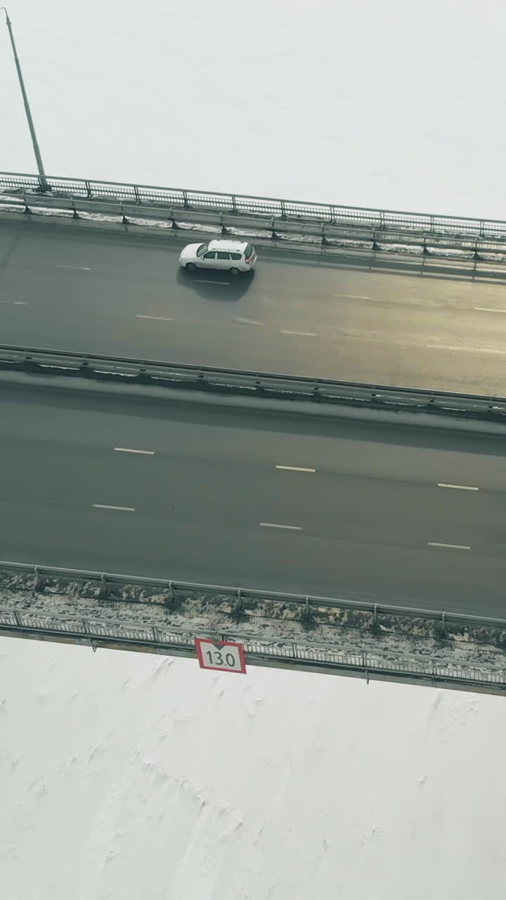 trucks and cars drive along modern bridge over white frozen river against city buildings close upper view