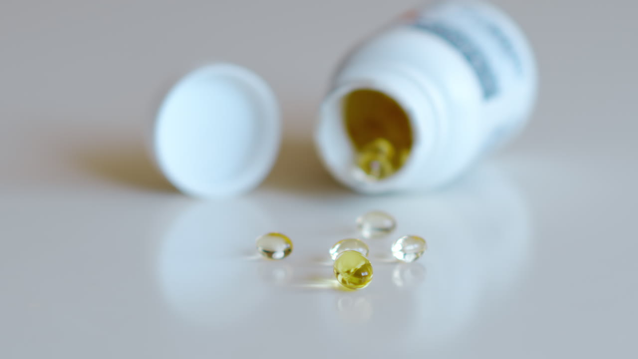 Fish oil omega 3 supplements spilling out of a packer bottle on a white background