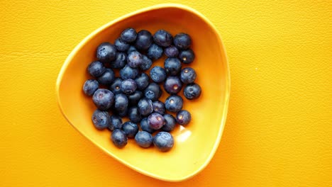 hand picking blueberries from a bowl