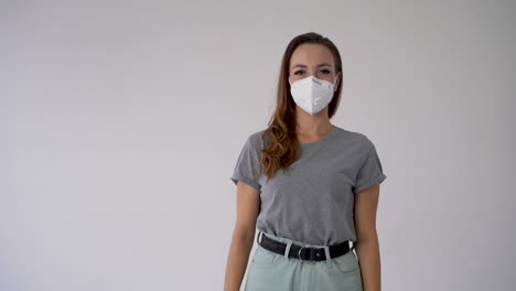 Young-woman-with-hand-aside-pointing-an-empty-blank-space-and-wearing-medical-face-mask.-Copy-space-and-white-background.-Frontal-view.