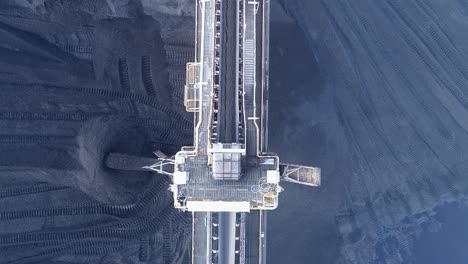 toma de drones de arriba hacia abajo de la planta de la mina de carbón, carbón que sale de la cinta transportadora con camiones mineros de orugas que mueven el carbón alrededor