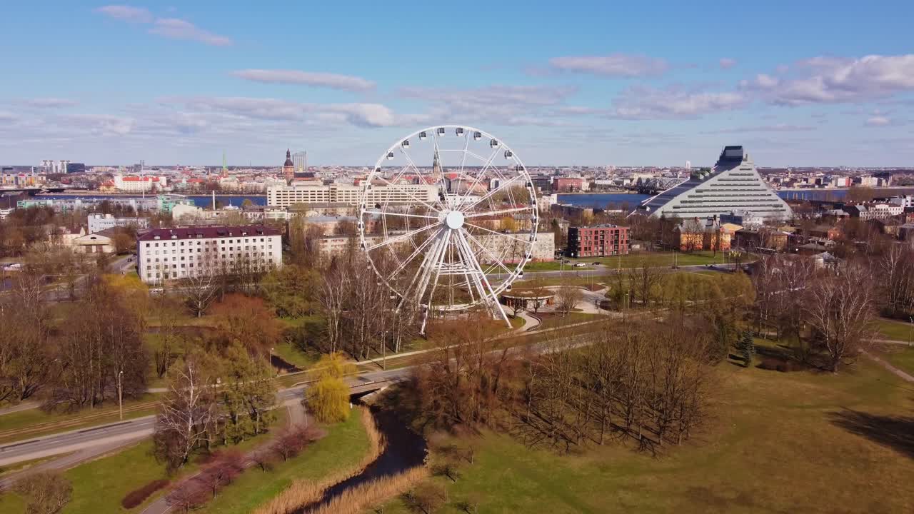 Ferris wheel in green park with Riga skyline in background, aerial view