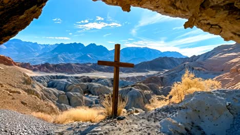 a wooden cross in the middle of a rocky landscape