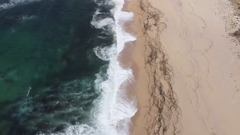 arial shot flying along a beach and ocean waves