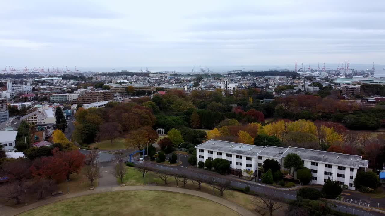 una ciudad vibrante con árboles de otoño y un puerto lejano, cielo nublado, estado de ánimo sereno, vista aérea