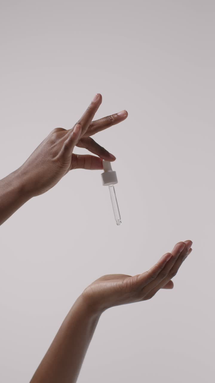 primer plano de una mujer exprimiendo el gotero de una botella de producto de belleza sobre un fondo blanco 2