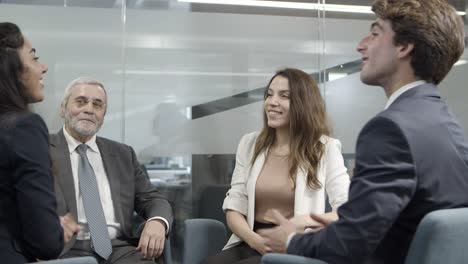 Cheerful-colleagues-sitting-on-chairs-and-shaking-hands