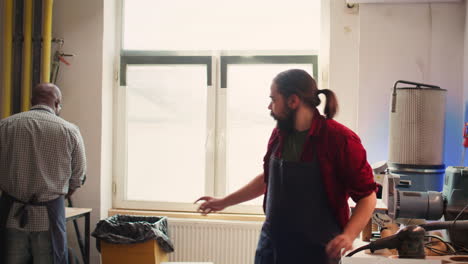 Man-wearing-protective-equipment-while-using-angle-grinder-to-sander-plank