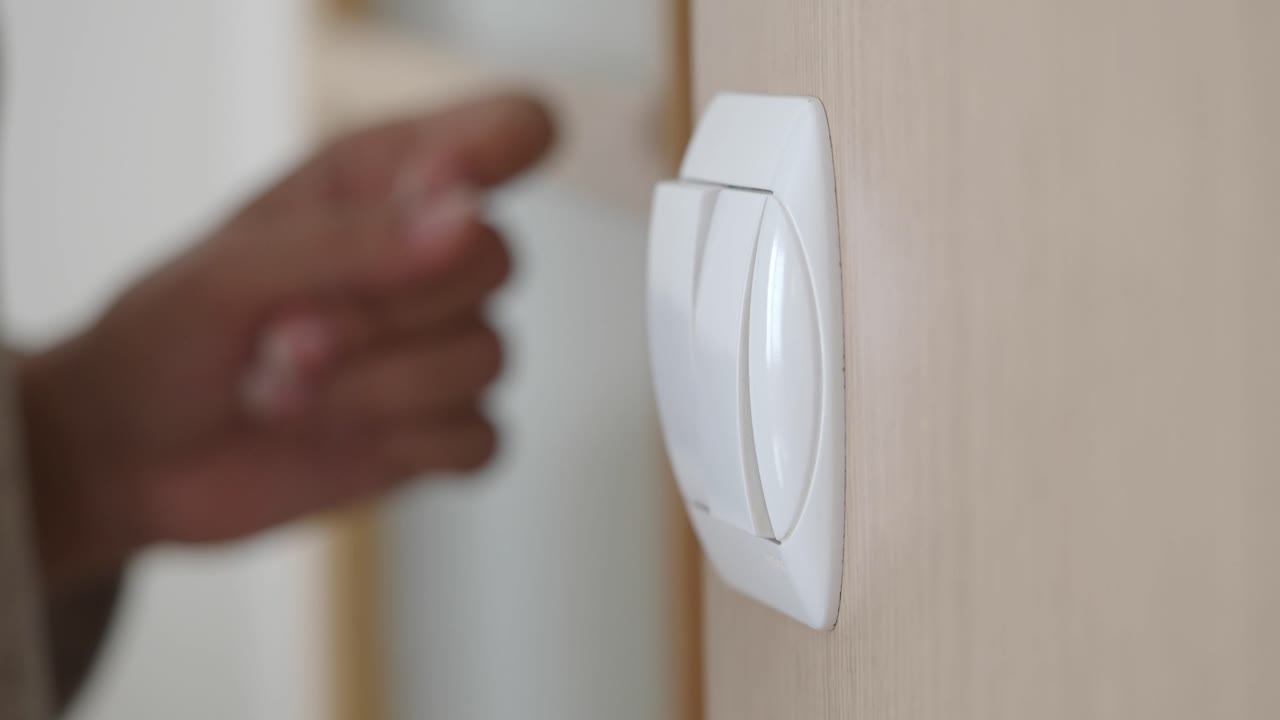 Close-Up of Hand Turning Light Switch On and Off