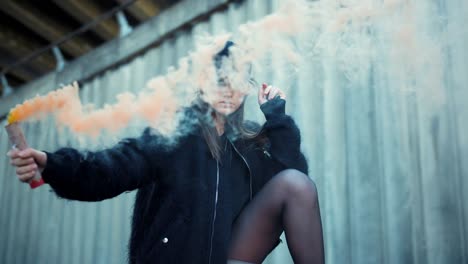 woman posing at camera with smoke bomb in hand. girl waving smoke grenade