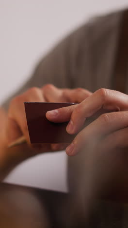 man applies special glue onto leather details edge at workplace closeup. leathersmith processes material to make accessory. handicraft home studio