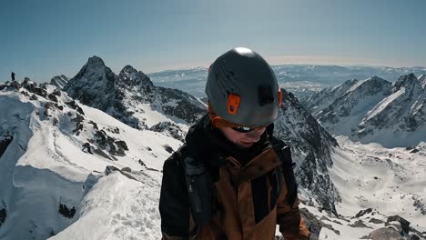 climber reaching the snowy summit of a mountain and high five with friend