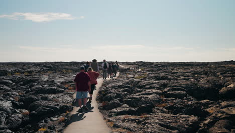group of people hiking through a volcanic lava field