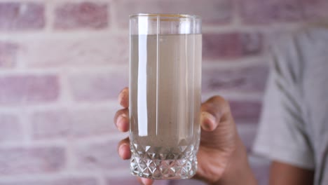 sosteniendo un vaso sucio de agua