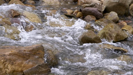 clear stream running through stone boulders abundant river flowing in slow motion