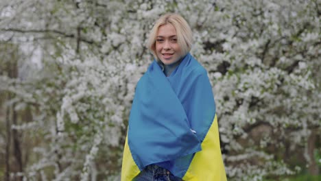 woman with ukrainian flag in blossom garden