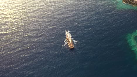 Aerial-drone-view-video-of-beautiful-sail-boat-cruising-in-the-deep-blue-Aegean-sea-during-sunset,-Santorini,-Greece