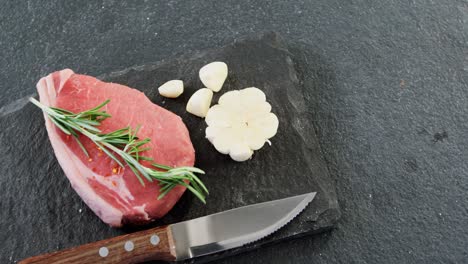 trozo de filete, cuchillo y ajo en la tabla de cortar
