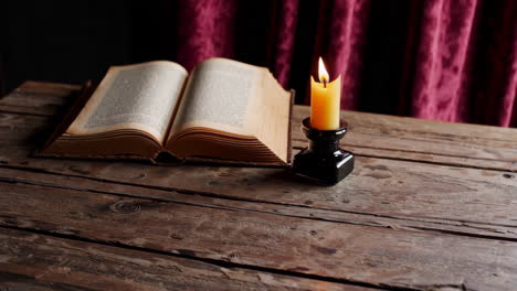 open book and candle on wooden table