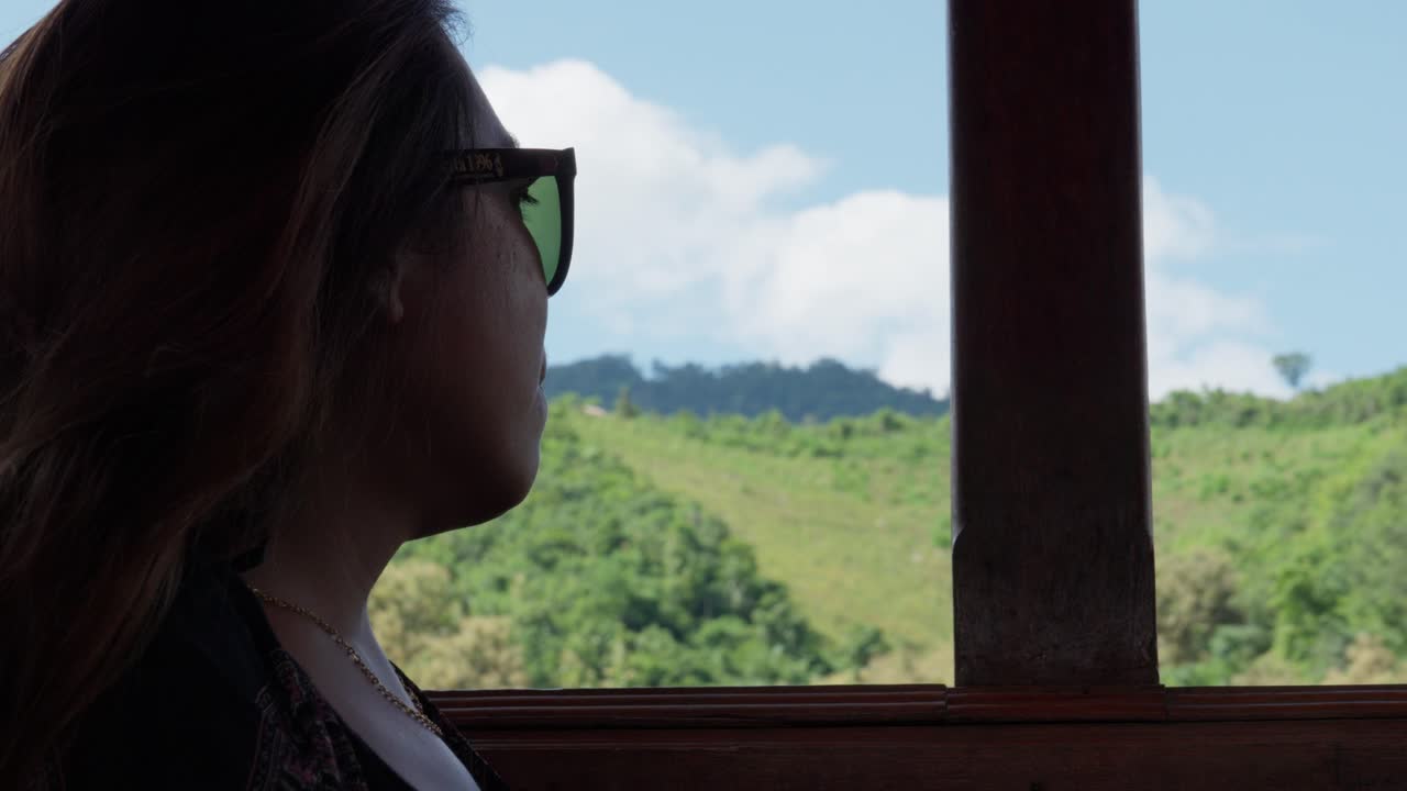 Asian woman on a boat trip with lush green background, slow-motion