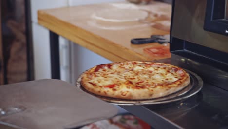 hot delicious pizza. pizzeria master takes out ready pizza from the oven. chef is pulling out fresh pizza with a special pizza spatula in the kitchen.
