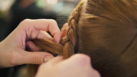 Manos-De-Una-Peluquera,-Está-Trenzando-La-Trenza-Para-Una-Modelo-De-Cabello-Rubio,-De-Cerca