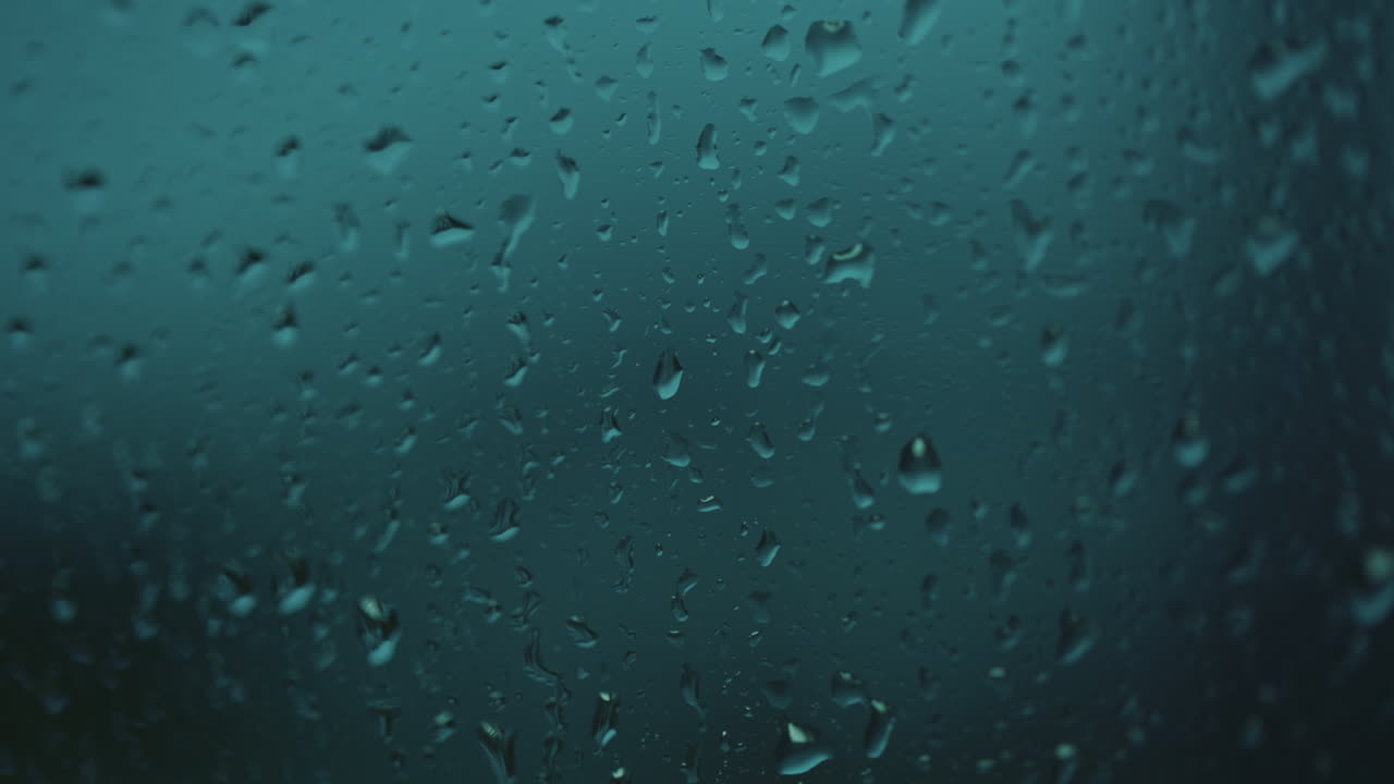 gotas de agua de lluvia cayendo sobre el cristal de la ventana azul