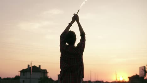 Young-Woman-Standing-With-Firework-Candles-During-Sunset-And-Looking-In-The-Camera