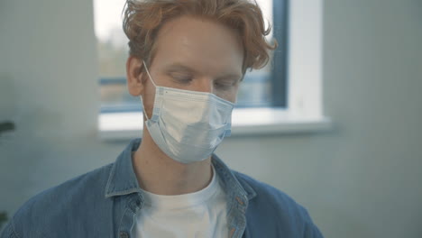 Portrait-Of-Young-Handsome-Redhead-Man-Talking-On-The-Phone-With-Face-Mask-Indoor