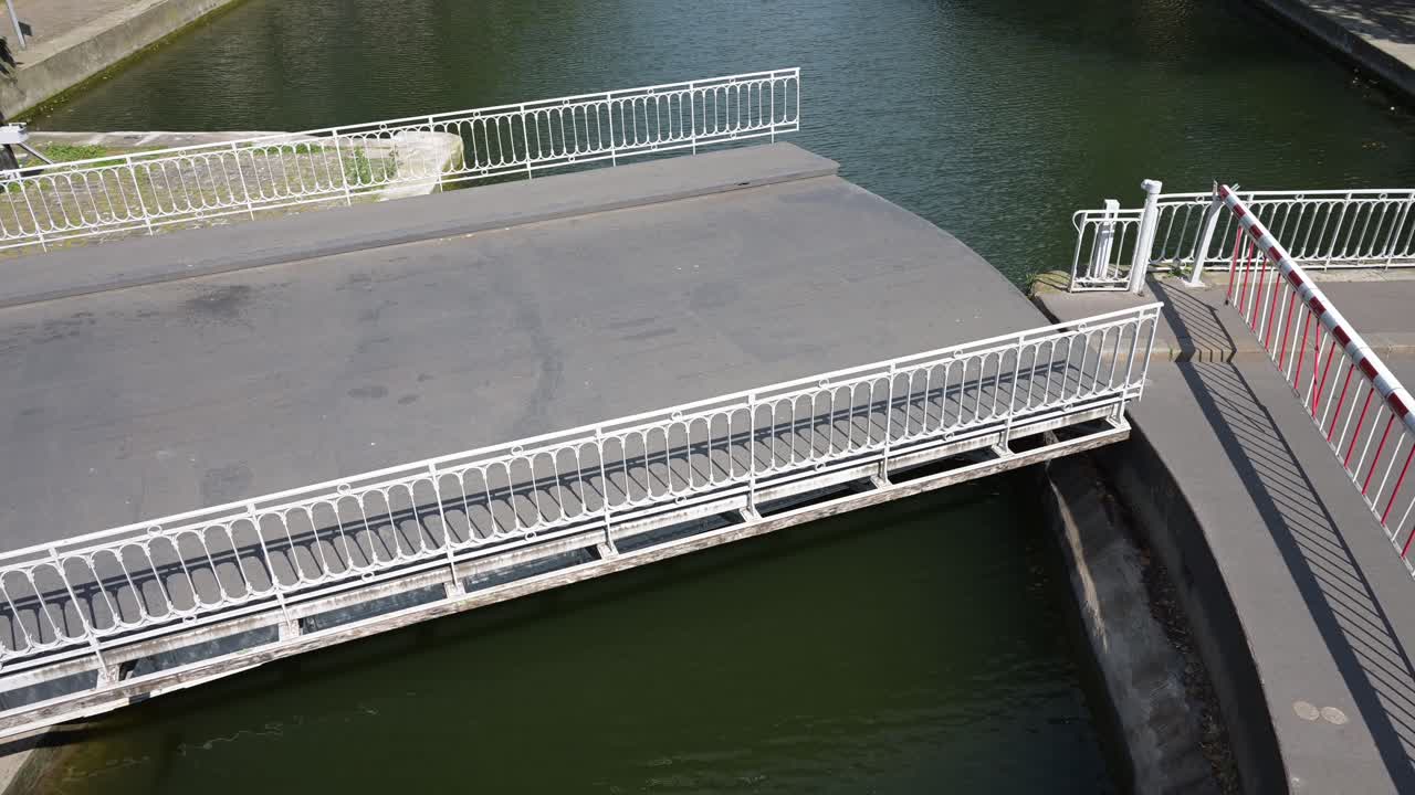 A mobile bridge over the Saint-Martin canal is opening to let the boats to pass through and out of the Seine River in Paris