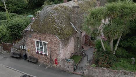 Charming-old-Cockington-thatched-cottage-in-Devon-England-aerial-low-orbit-right