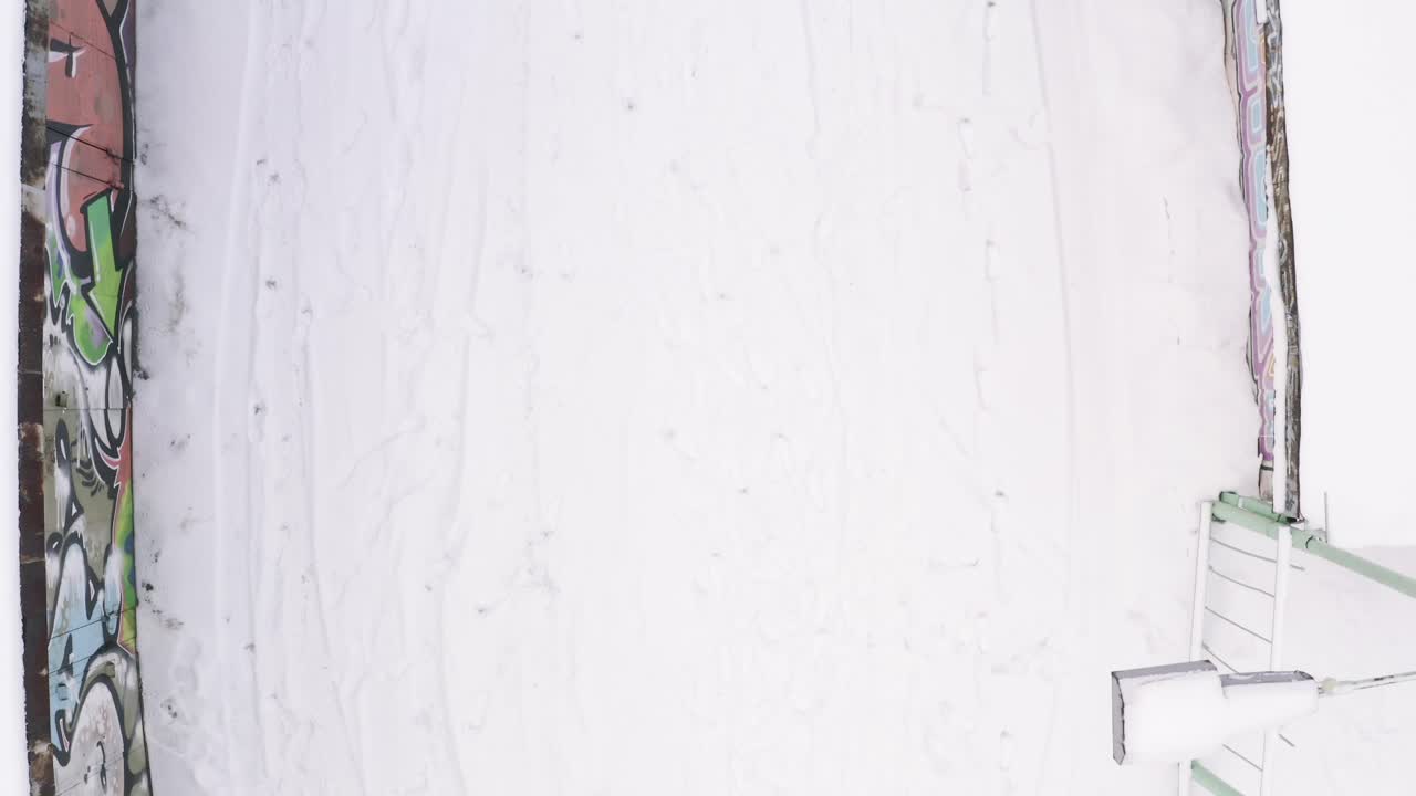 persona caminando en una zona urbana nevada con graffiti