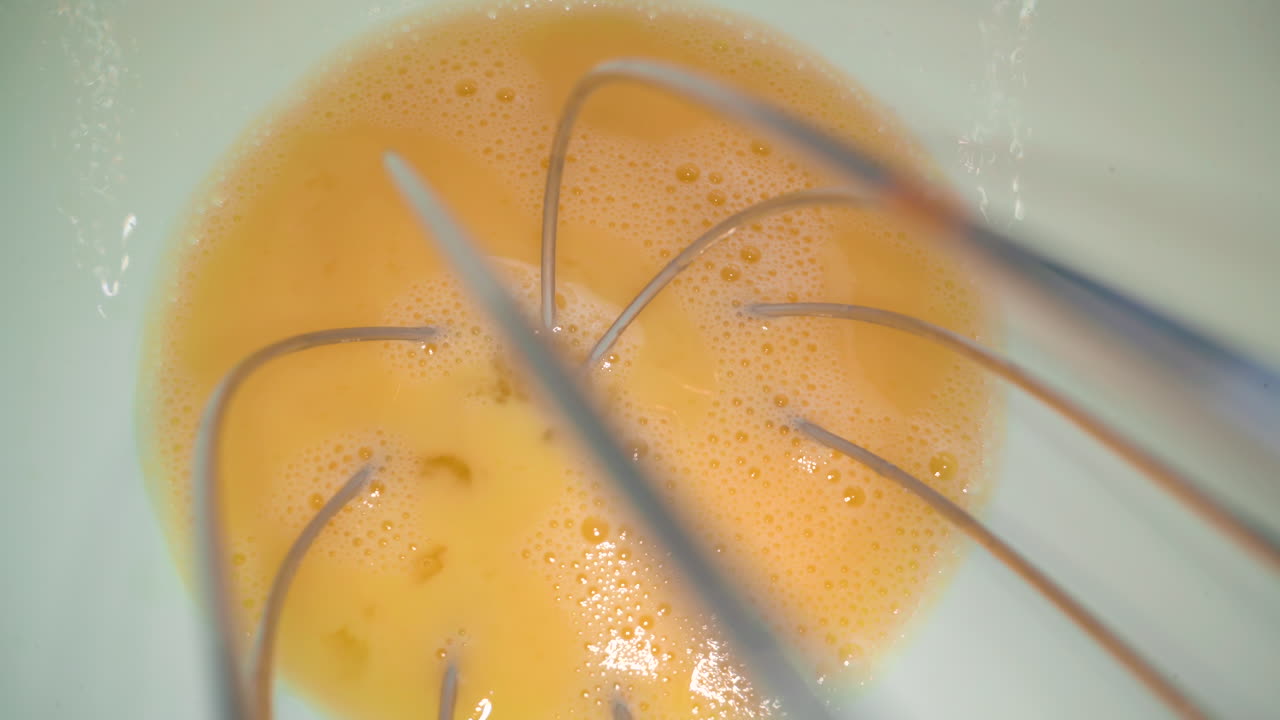 huevo de pollo espumoso y batido en un cuenco de cerámica blanca de cerca