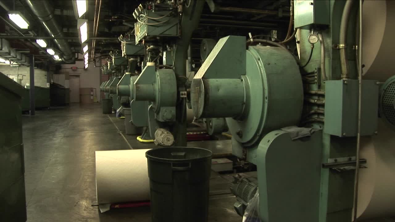 노동자들은 신문 공장에서 종이 롤러를 본다