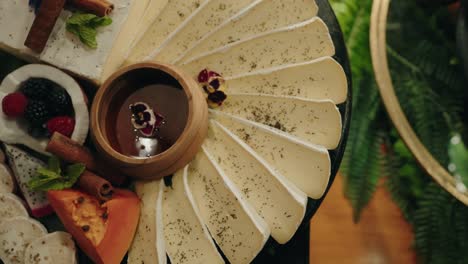 arranged cheese platter with fruit and chocolate dip centerpiece