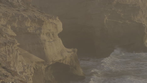 coastal cliffs with caves and waves at sunrise/sunset