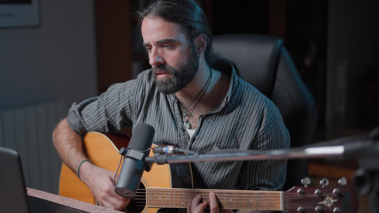 hombre tocando la guitarra acústica en el estudio casero