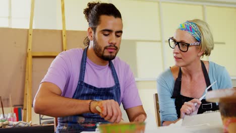 Drawing-teacher-assisting-man-in-pottery-4k